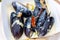 Mussels cooked in wine sauce with herbs in large frying pan