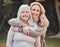 She must get her good looks from her mom. a woman standing outside with her elderly mother.