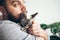 Muzzle of a cat and a beard mans face. Close-up of handsome young man and tabby kitten.