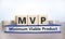MVP, minimum viable product symbol. Wooden cubes on book with words MVP, minimum viable product. Beautiful white background.
