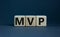 MVP, minimum viable product symbol. Wooden cubes with the word MVP, minimum viable product. Beautiful grey background. Business