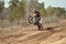 MX racer standing in motion performed a wheelie