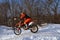 MX winter motocross racer on a motorcycle arrives on a snowy hill