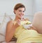 My baby loves salad as much as I do. a beautiful pregnant woman relaxing on the sofa while eating a fresh salad.