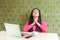 My God, please help me! Portrait of young girl freelancer with black dreadlocks in pink blouse, sitting in cafe and holding palm