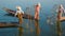 Myanmar, Inle Lake. Fishermen on boats demonstrate ancient way of fishing