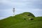 Mykines lighthouse and cliffs on Faroe islands. Hiking landmark. Denmark