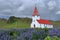 Myrdalskirkja with Dark Clouds over Field of Lupines at Vik i Myrdal, Southern Iceland