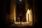 Mysterious blonde woman in elegant retro coat with old oil lantern walking in old French street in