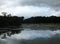 Mysterious dark evening lake with dramatic clouds reflected in the water and trees along the shore