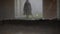 The mysterious figure of a man in a black cloak is on a dusty room in the direction of the camera.