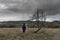 A mysterious hooded figure. Standing next to a tree on a moody winters day