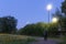 A mysterious hooded man, looking up at a street light. On a spring evening