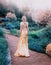 Mysterious lady in chic yellow expensive luxury dress in magnificent garden, mysterious princess with long blond hair