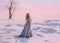 Mysterious lady from Middle Ages with dark hair in gentle gray blue dress in snowy desert with open back and shoulders