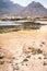 Mysterious landscape of sandy coastline with fisher village and black volcanic mountains in background. Baia Das Gatas