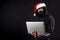 Mysterious male santa hacker holding laptop computer