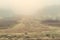 Mysterious sandy dirt road covered with heavy fog in early autumn morning. Pine trees with thick fog along village road. Scenic