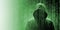 Mysterious silhouette of a hooded hacker beneath a digital green rain of binary code characters