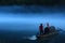 Mysterious view of a man on the wooden boat rowing on the misty lake