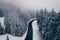 Mysterious Winter road in the forest. Aerial view the a winding mountain road at Cheia, Romania