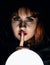 Mysterious young woman wonders on a large luminous ball and raised a finger to her lips. on a dark background