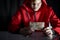 Mystery man in red hoodie holding euro banknote