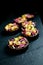 Mystic dark chocolate pralines with candied orange and red knapweed petals on dark background