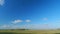 Mystic white clouds flying over green autumn field. Clouds fly across the blue sky. Timelapse.