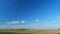 Mystic white clouds flying over green autumn field. Clouds fly across the blue sky. Timelapse.