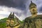 Mystical 4 stone buddha heads statues, dark storm clouds - Buddha Park Wat Xieng Khuan, Vientiane, Laos