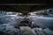 Mystical picture of water flowing under small bridge with ice and cold weather
