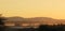 Mystical scenic hilltop landscape photograph with white and orange mist clouds under an orange sky