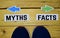 Myths or Facts opposite direction signs with sneakers on wooden