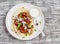 Naan bread with chicken vegetable stir fry and yogurt sauce on plate on rustic light wood background.