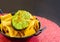 Nachos with avocado in black metal bowl, guacamole