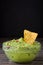 Nachos and guacamole on wood and black background