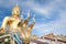 Naga and large gold buddha statue under construction in Thai temple with clear sky.WAT MUANG, Ang Thong, THAILAND.