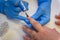 Nail care in the beauty salon. Beautician in medical gloves covers the client`s nails with a colorless varnish, close-up.