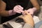 In the nail salon client manicurist in gloves handles nails with a spatula for manicure