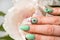 Nails Design. Hands With Bright Green Manicure with flowers. Close Up Of Female Hands. Art Nail