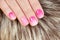 Nails with manicure covered with pink nail polish on fur background