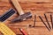 Nails, old hammer, pencil and measuring angle on wooden background.