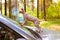 Naked bald Sphynx cat on car hood in woods. Traveling with pet Feline animal.