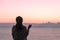 Naked beautiful female with wet hair wrapped in a blanket with cup of coffee standing on the glass balcony early morning at sunris