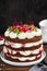 Naked Black forest cake, Schwarzwald pie. Cake with dark chocolate, whipped cream and cherry on a dark wooden background.