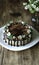 Naked drip cake with chocolate, decorated with strawberries, jasmine flowers and honeysuckle on brown wooden table