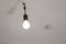 Naked dusty light bulb without lampshade hanging switched on from the ceiling in an empty apartment, fire alarm blurry in