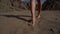 Naked female legs are walking over sand in desert, closeup of bare feet moving to camera