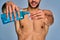 Naked guy with smile with a beard pours mouthwash from a bottle into the cap. Dental concept